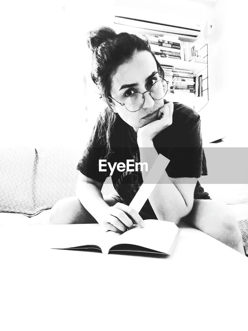 PORTRAIT OF YOUNG WOMAN SITTING BY BOOK