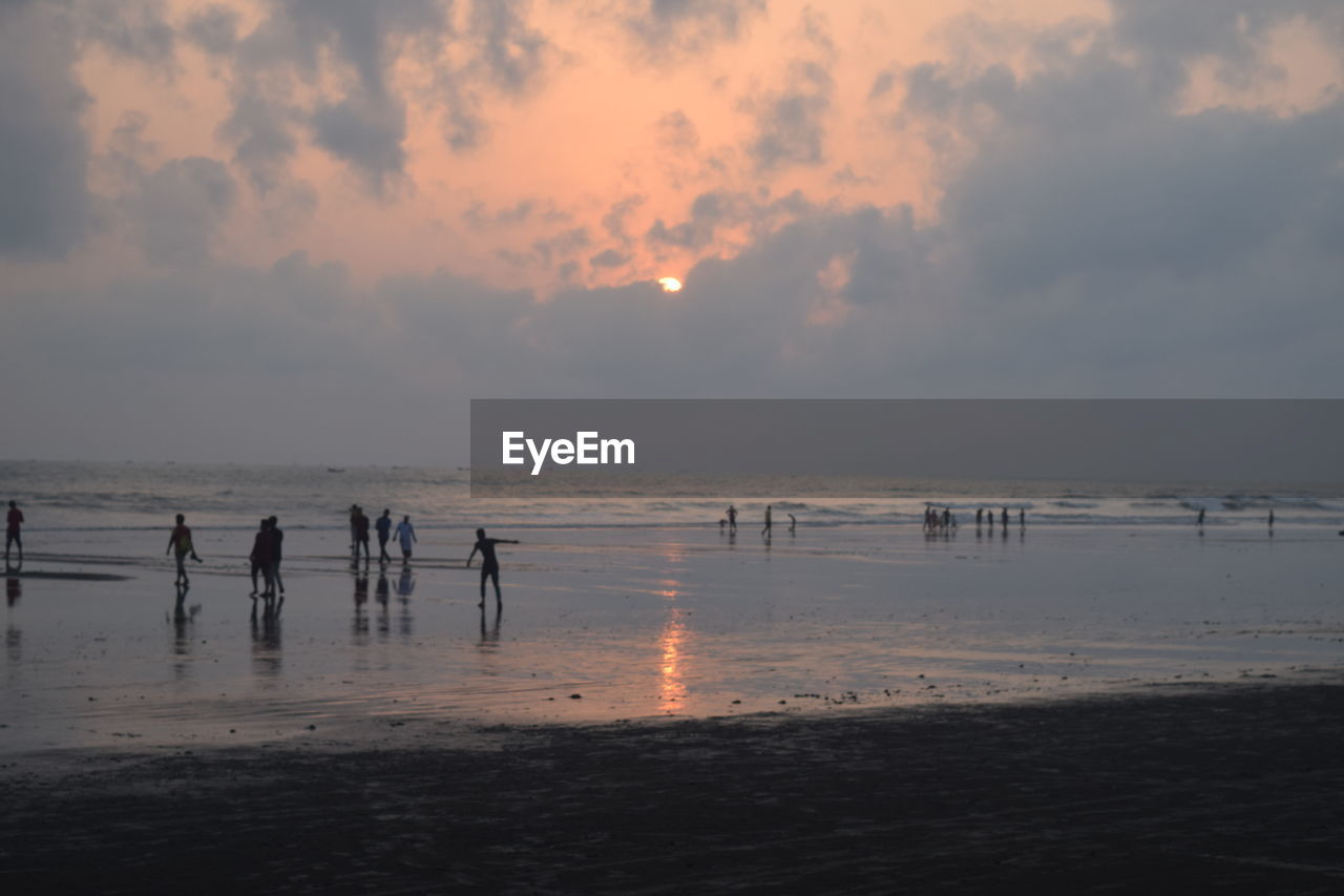 Silhouette people at beach against sky during sunset