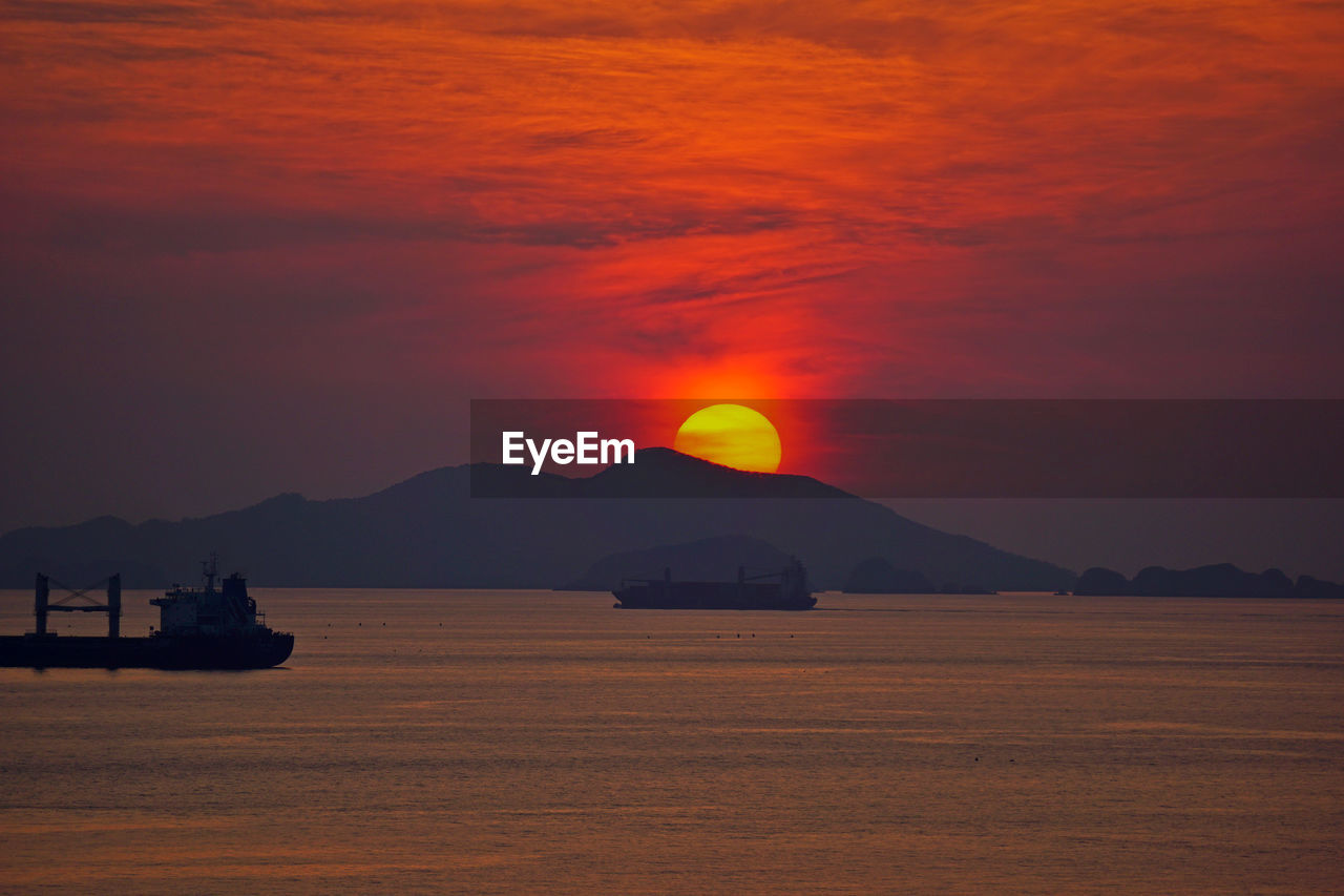 horizon, sunrise, sky, dawn, water, sea, mountain, afterglow, beauty in nature, ocean, scenics - nature, nature, morning, no people, tranquility, cloud, land, orange color, coast, nautical vessel, transportation, silhouette, tranquil scene, ship, red sky at morning, sun, travel destinations, outdoors, travel, mode of transportation, reflection, landscape, environment, idyllic, dramatic sky