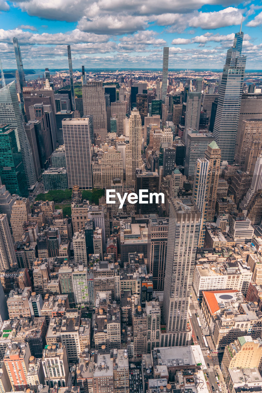 Aerial view of illuminated skyscraper buildings in city at day at high angle