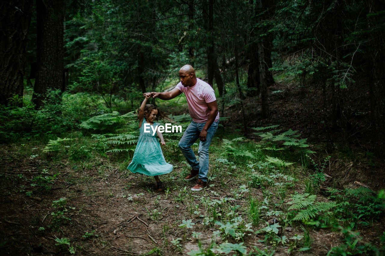 Father and daughter dancing in the middle of the forest