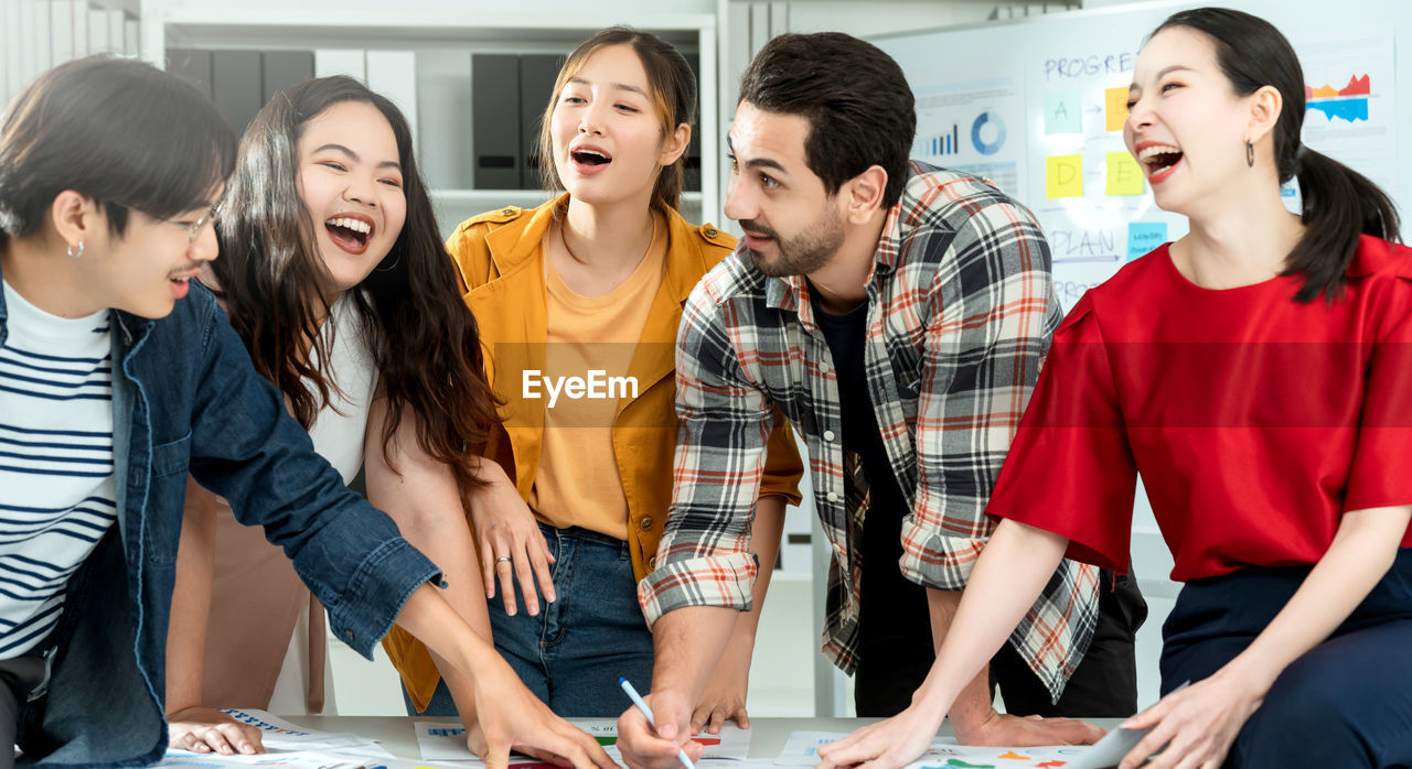 Cheerful colleagues discussing on desk in office