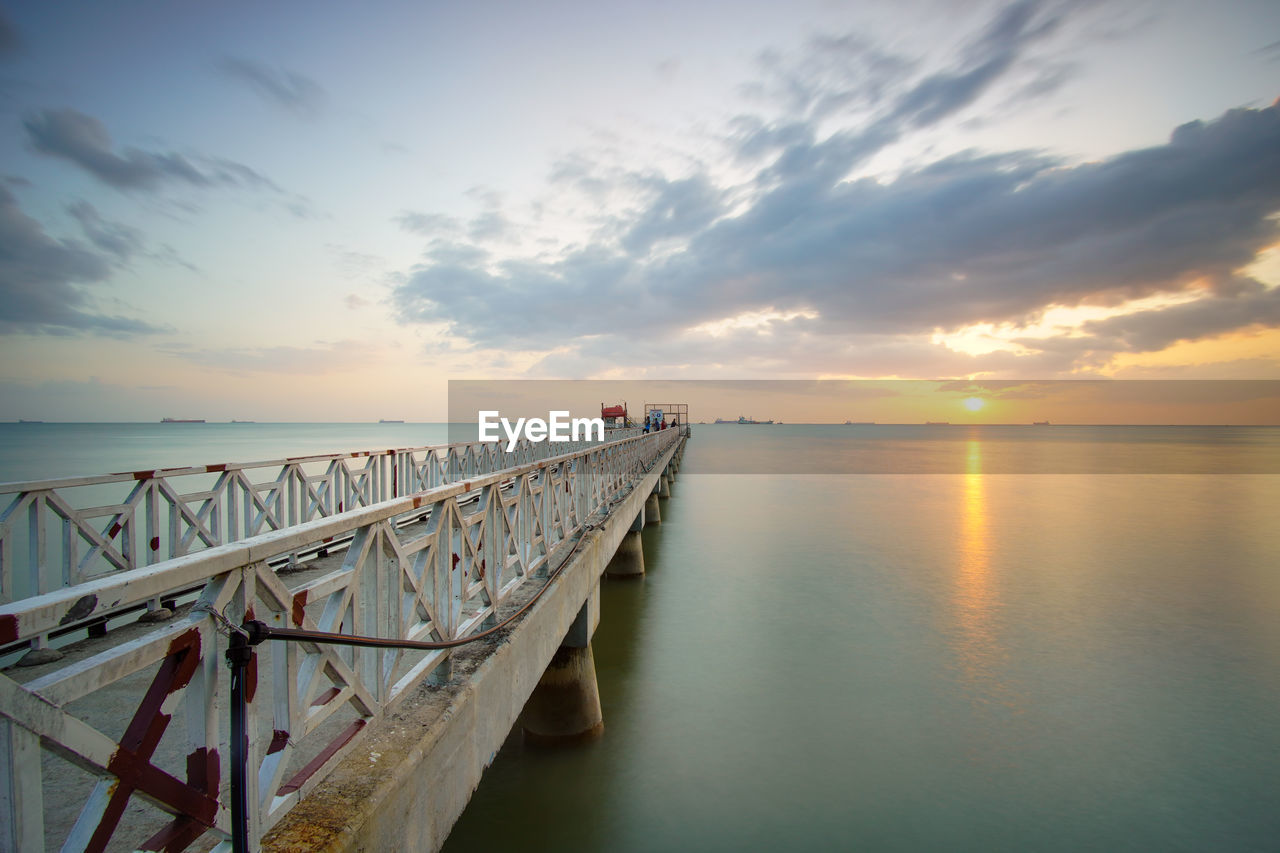 Pier over sea against sky during sunset