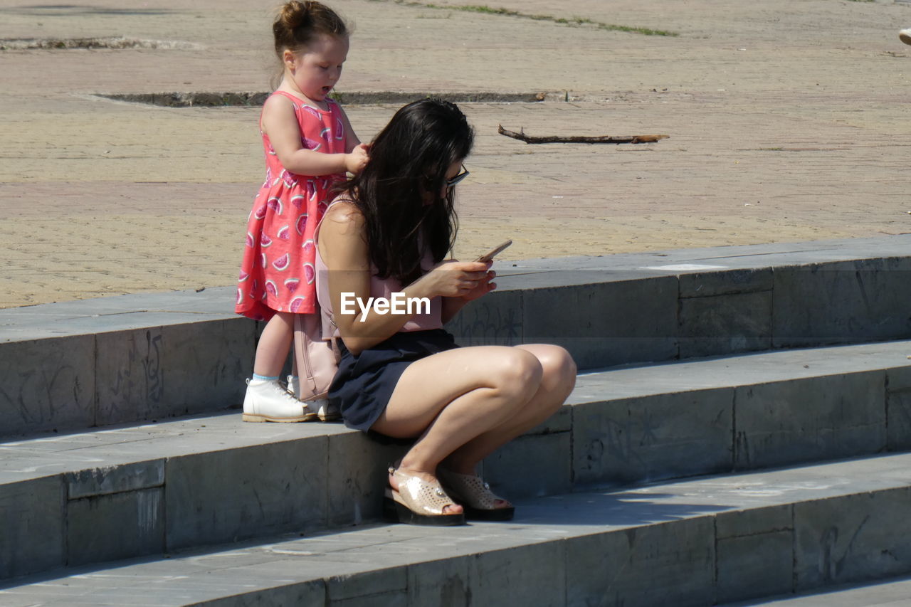 FULL LENGTH OF WOMAN SITTING OUTDOORS