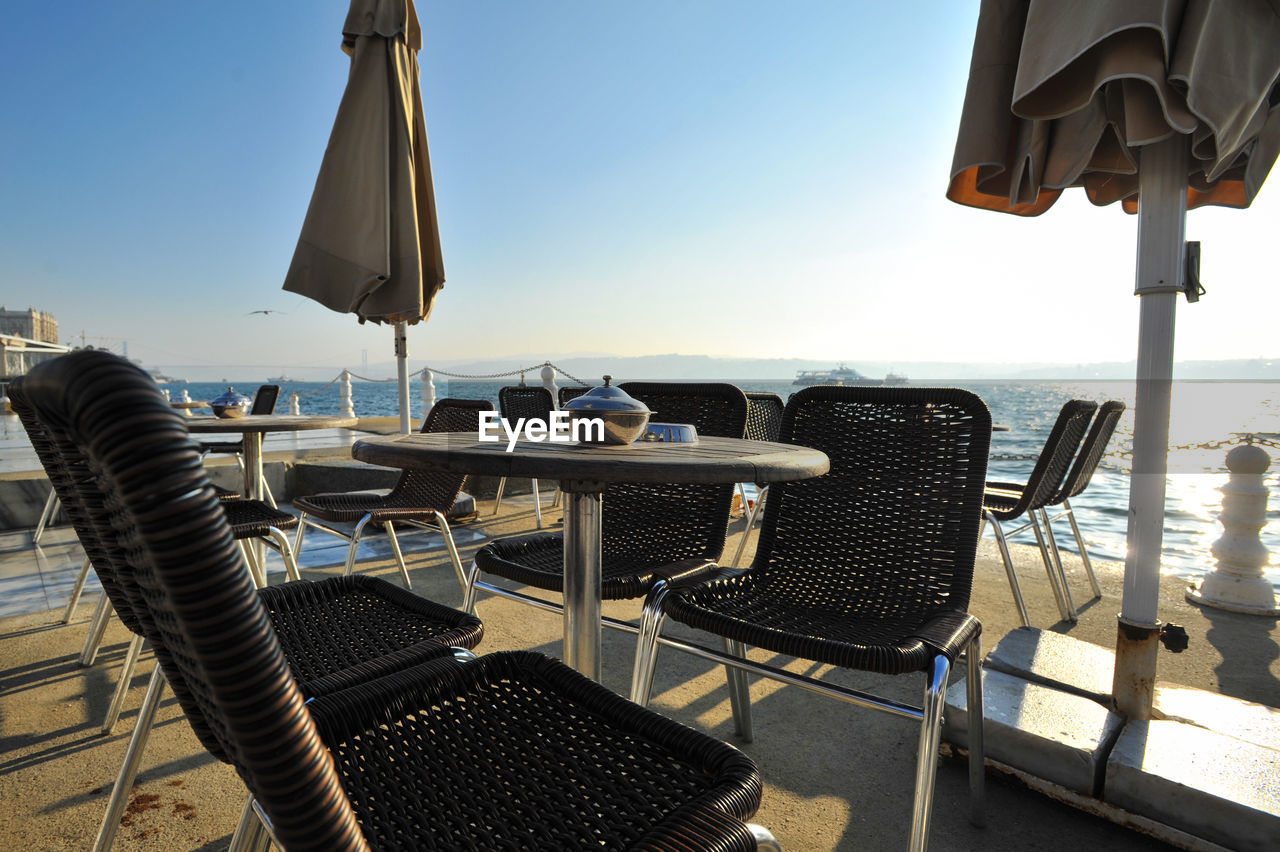 Empty chairs and tables at seaside