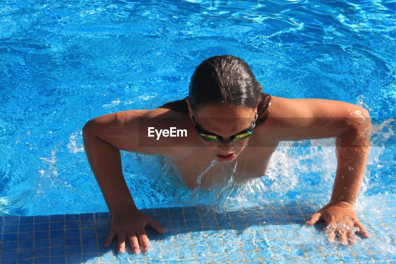 High angle view of shirtless man enjoying in swimming pool during summer