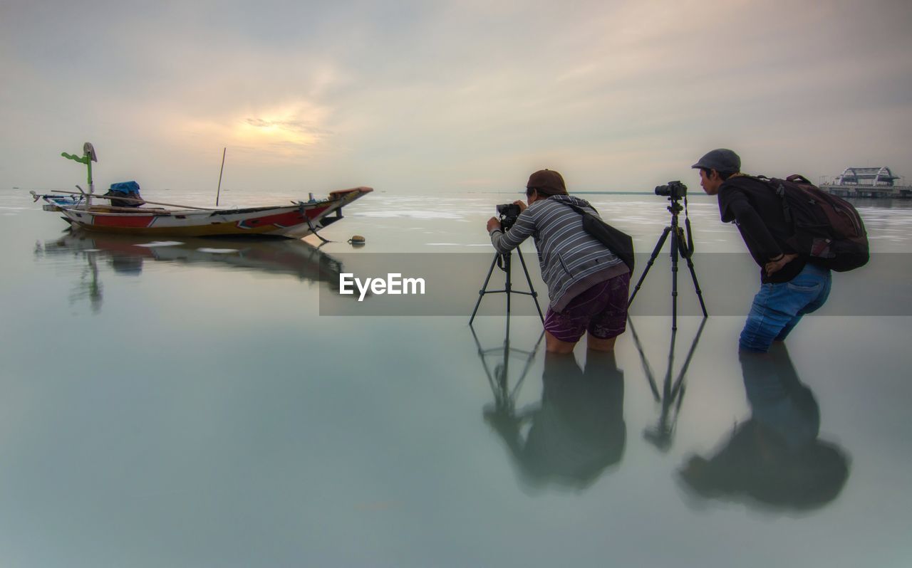 People photographing in sea against sky