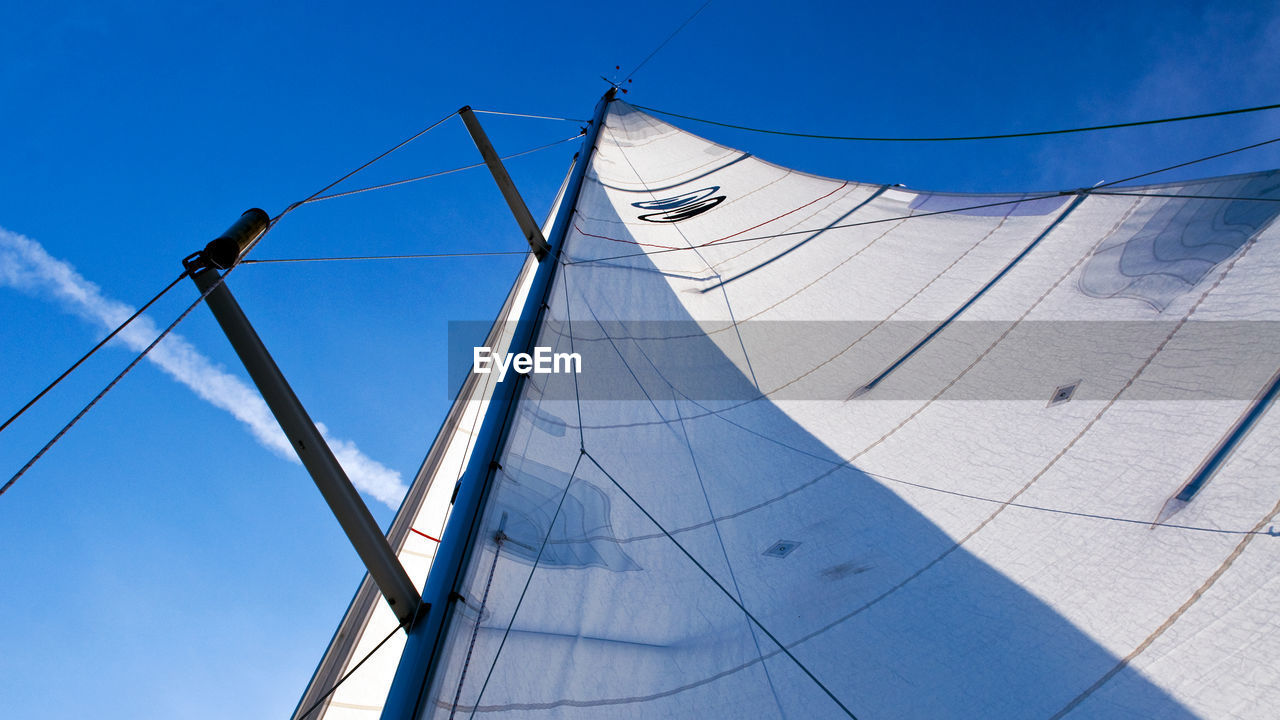 Low angle view of sailboat against blue sky