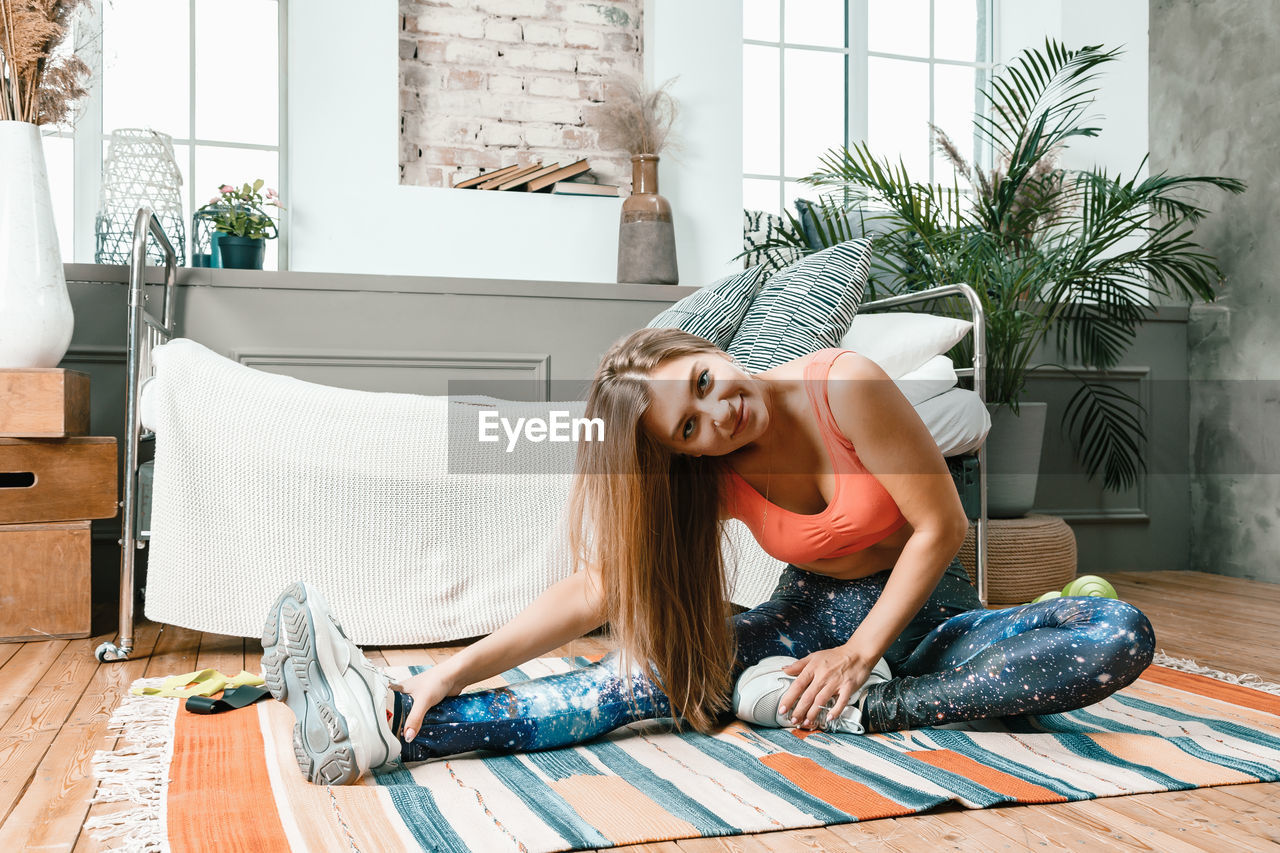 A young woman goes in for sports at home, online workout . the athlete stretching , meditating