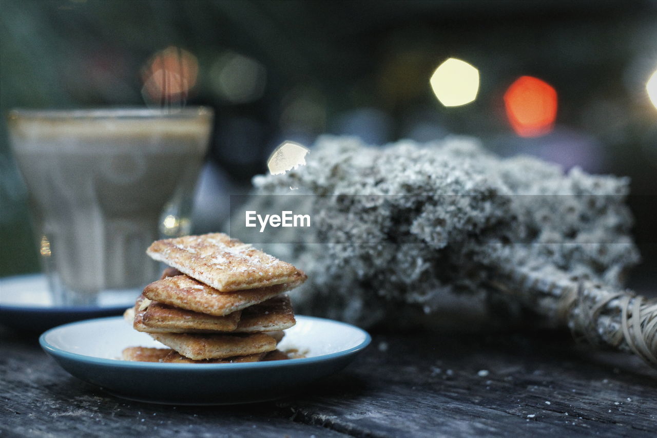 Stacked biscuits in plate by coffee on table