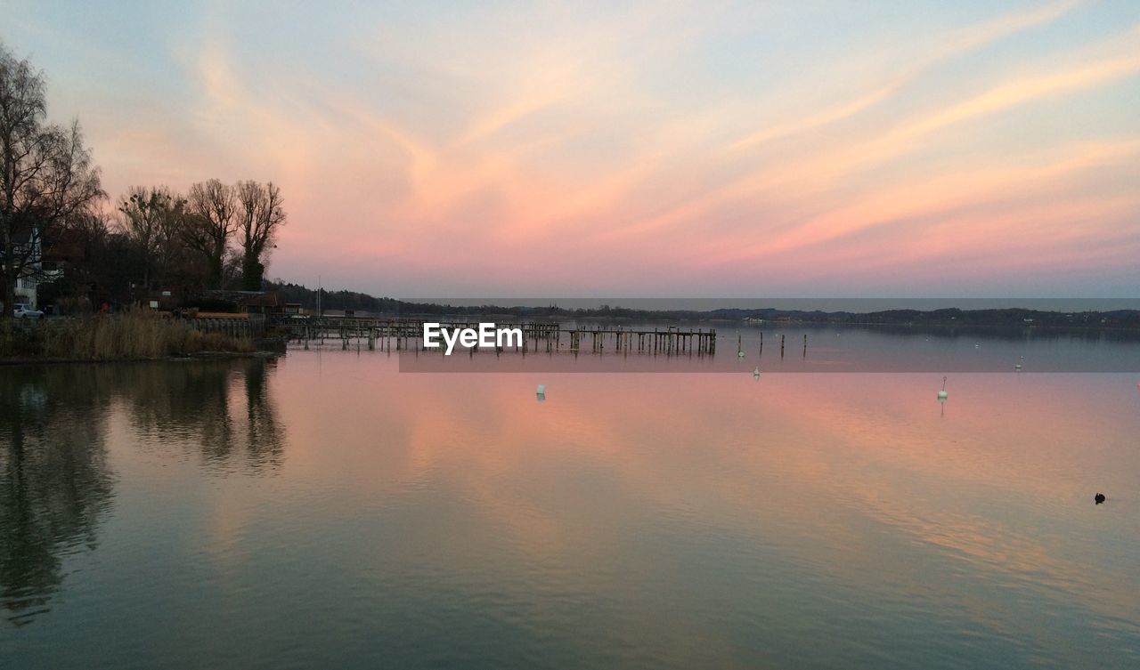 Scenic view of jetty in lake against sky during sunset