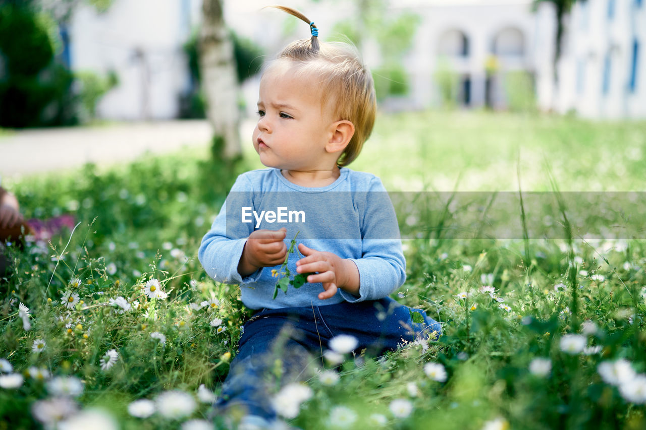 Cute girl looking away while sitting on grass