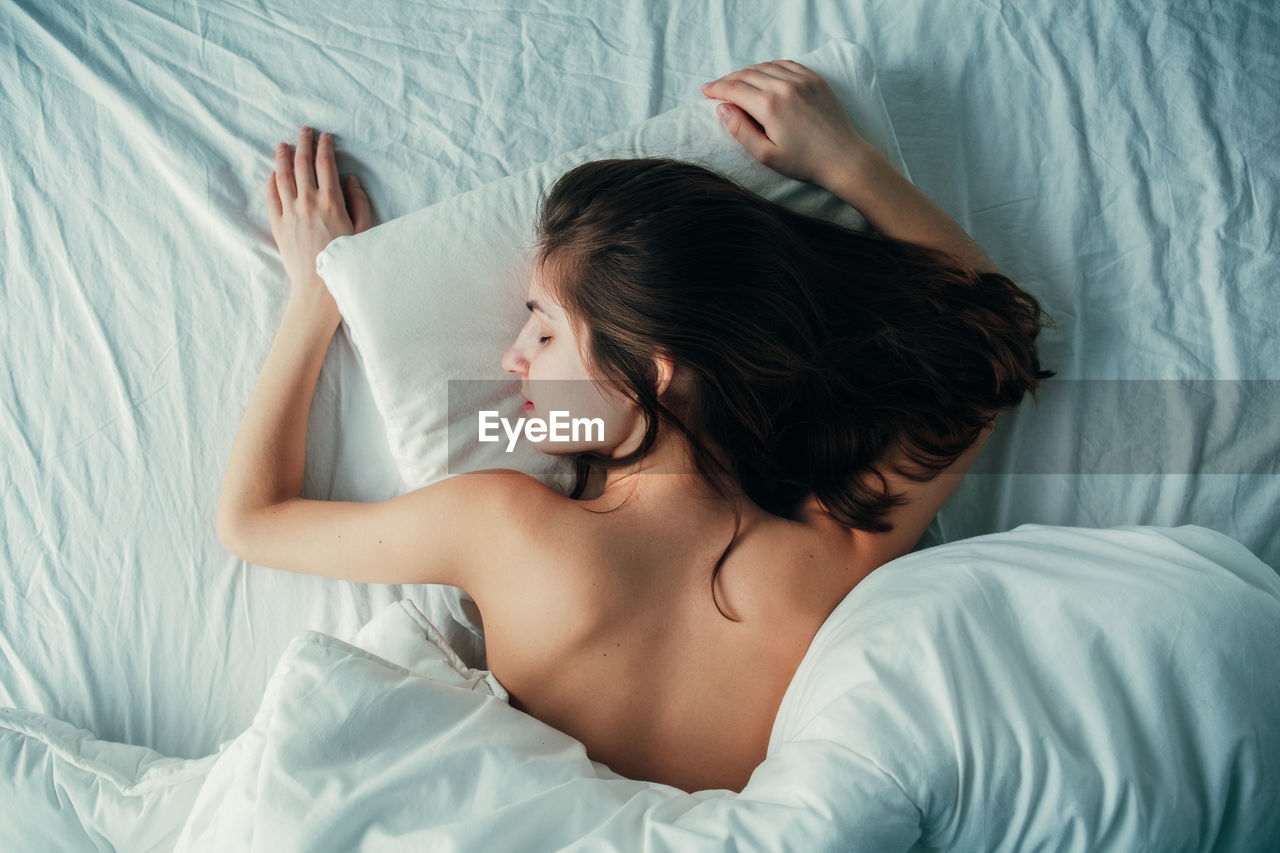 High angle view of shirtless woman sleeping on bed