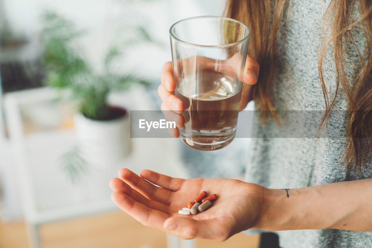 midsection of woman holding drink at table