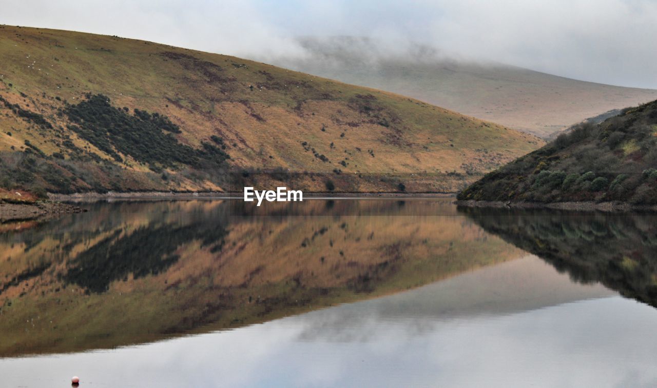 Scenic view of lake by mountains against sky