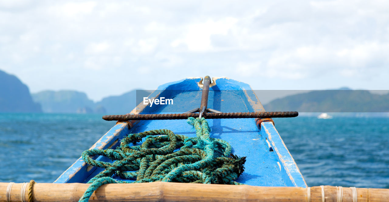 CLOSE-UP OF ROPE TIED ON BOAT AGAINST SKY