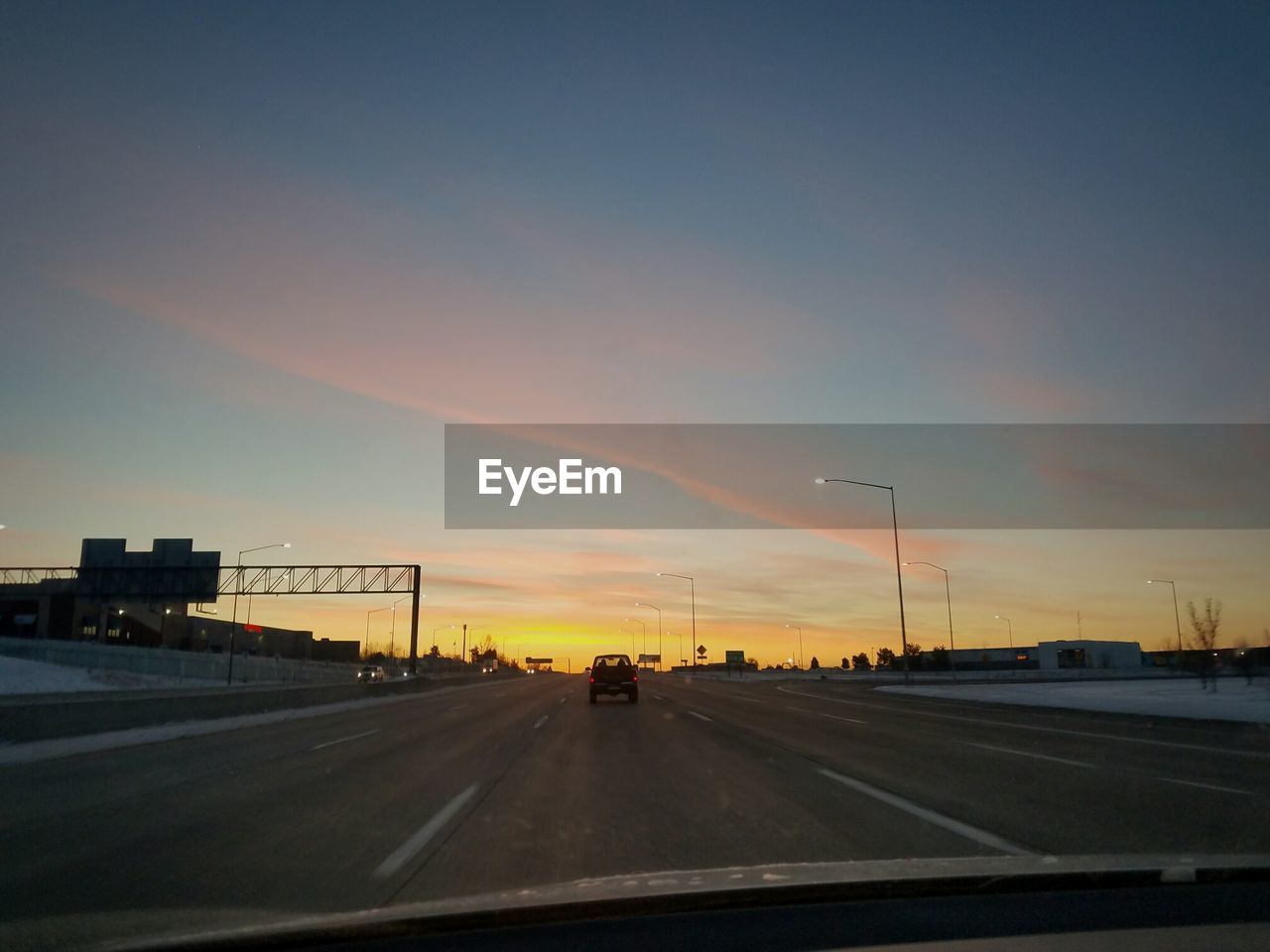 CAR ON ROAD AGAINST SKY AT SUNSET