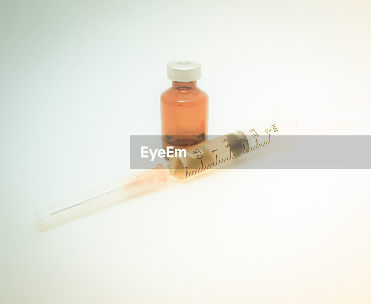 Close-up of syringe with vial on white table