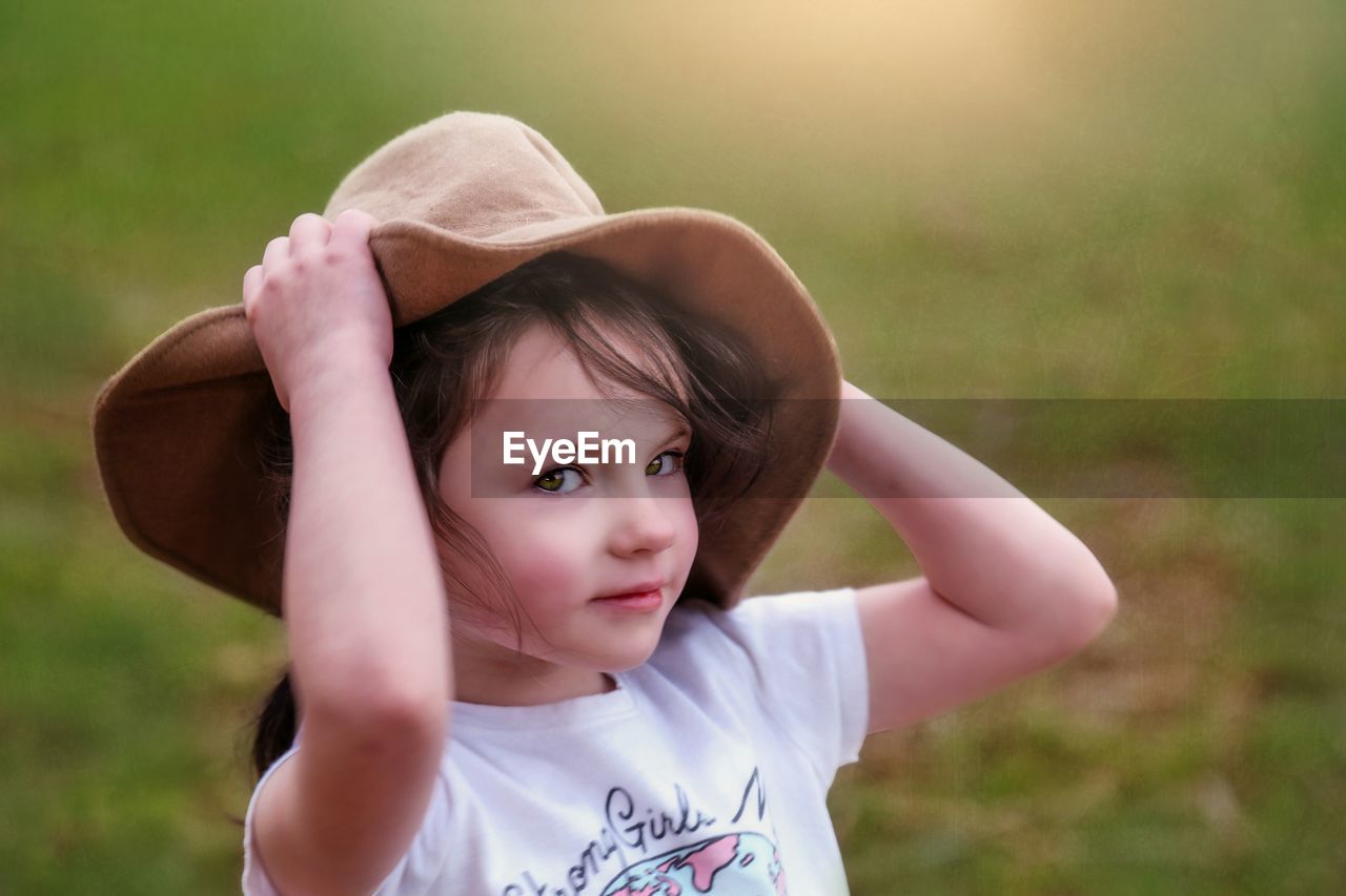 PORTRAIT OF CUTE GIRL WITH HAT IN BACKGROUND