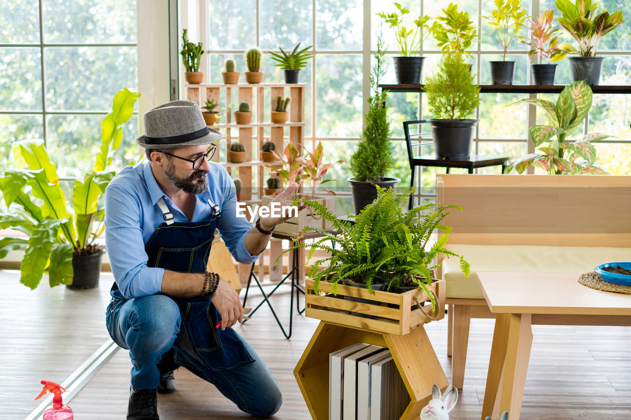 Young man sitting on chair by potted plant