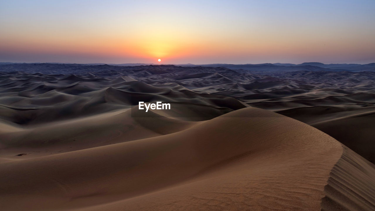 SCENIC VIEW OF DESERT AGAINST SKY AT SUNSET