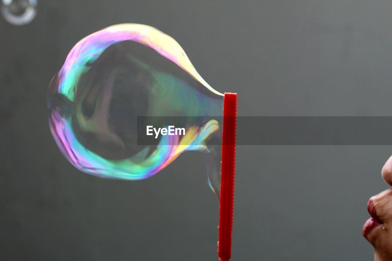 Close-up of woman blowing bubble on wand