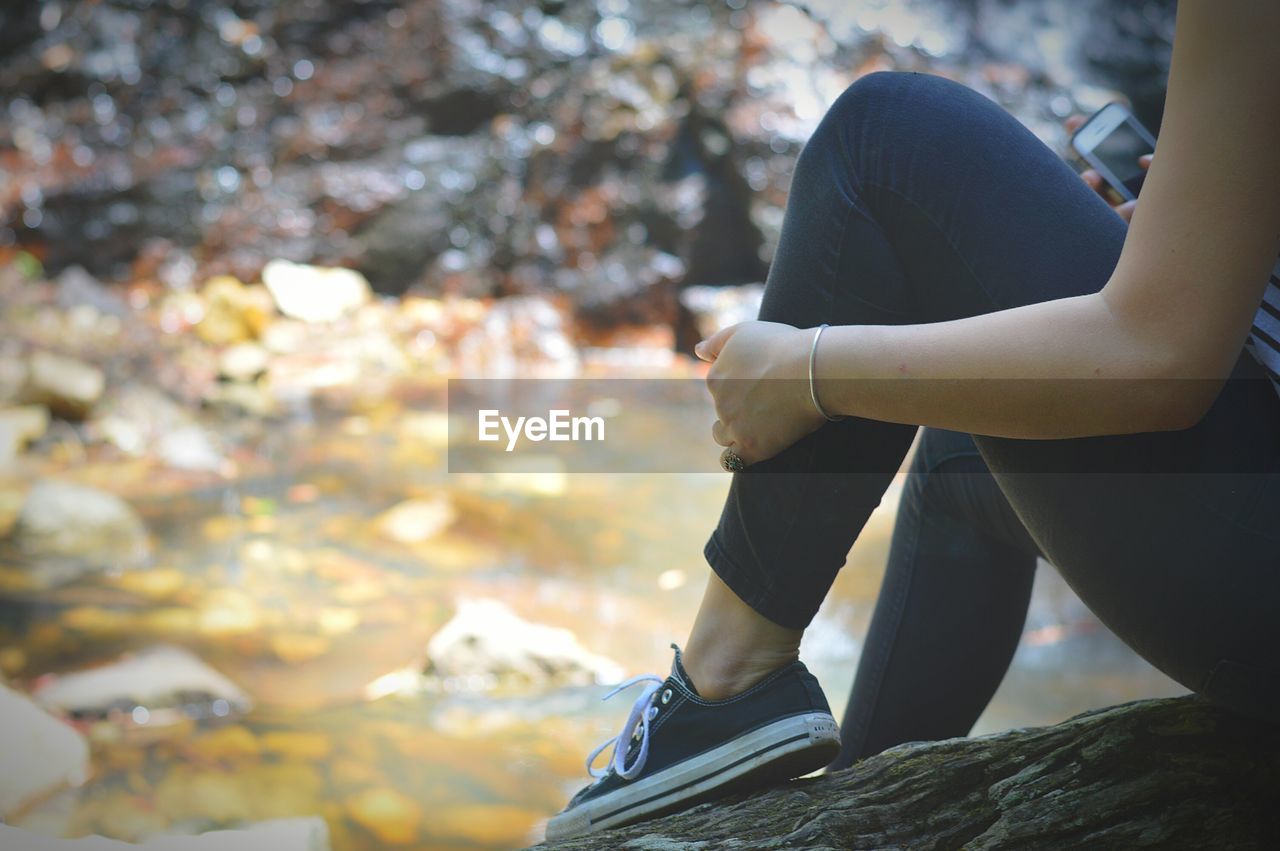 Low section of woman sitting on rock