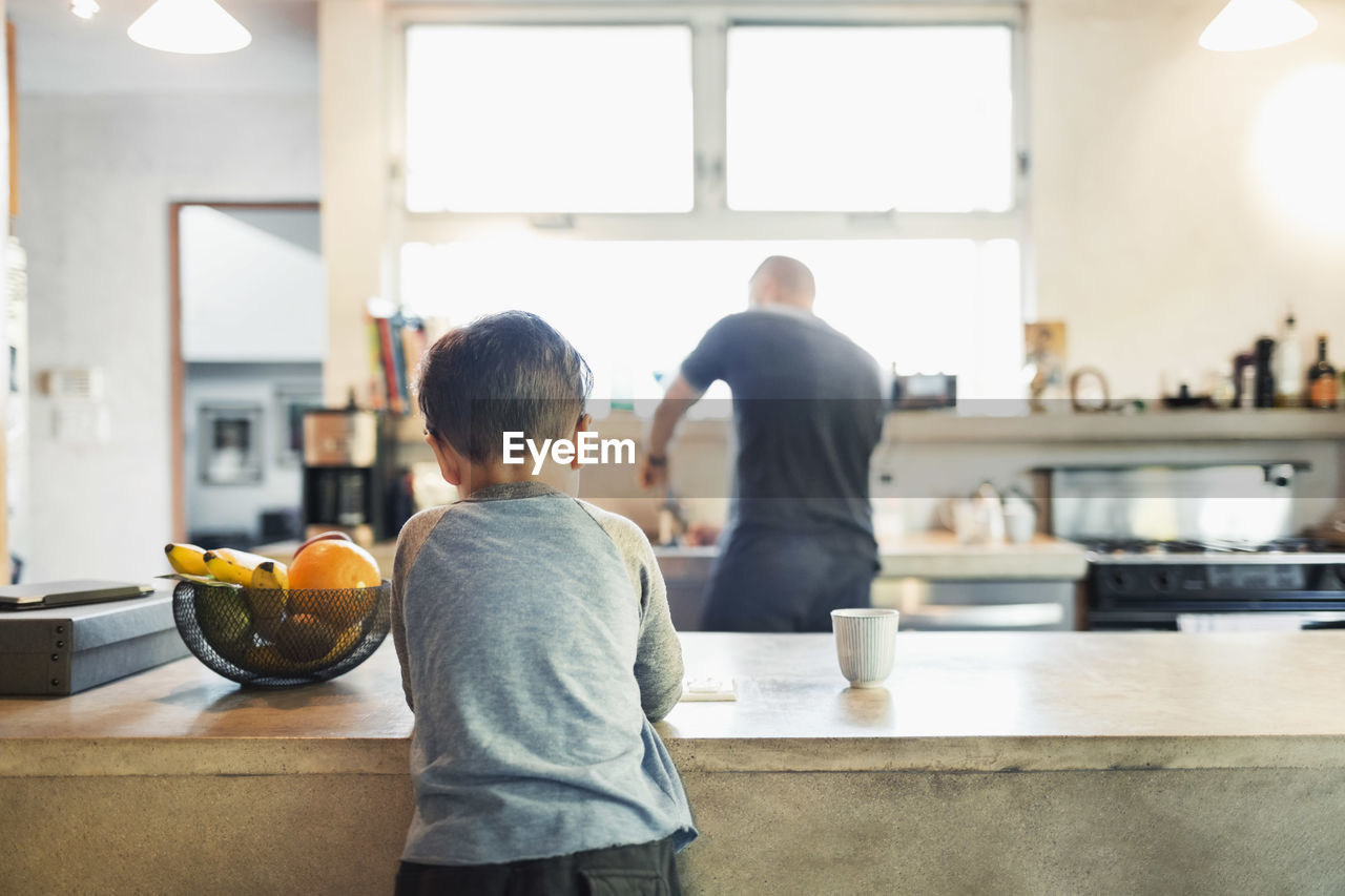 Rear view of father and son in kitchen