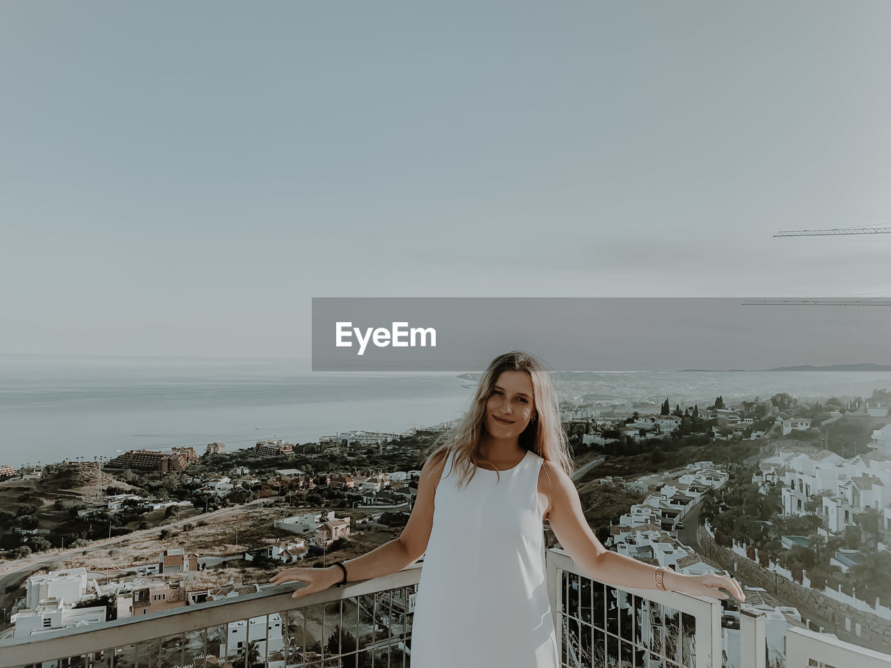 Young woman standing by sea against sky