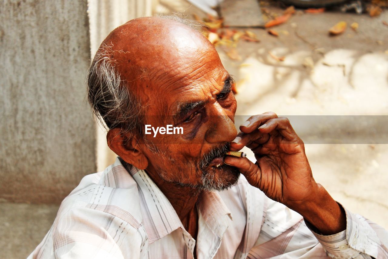 Mature man smoking beedi on footpath