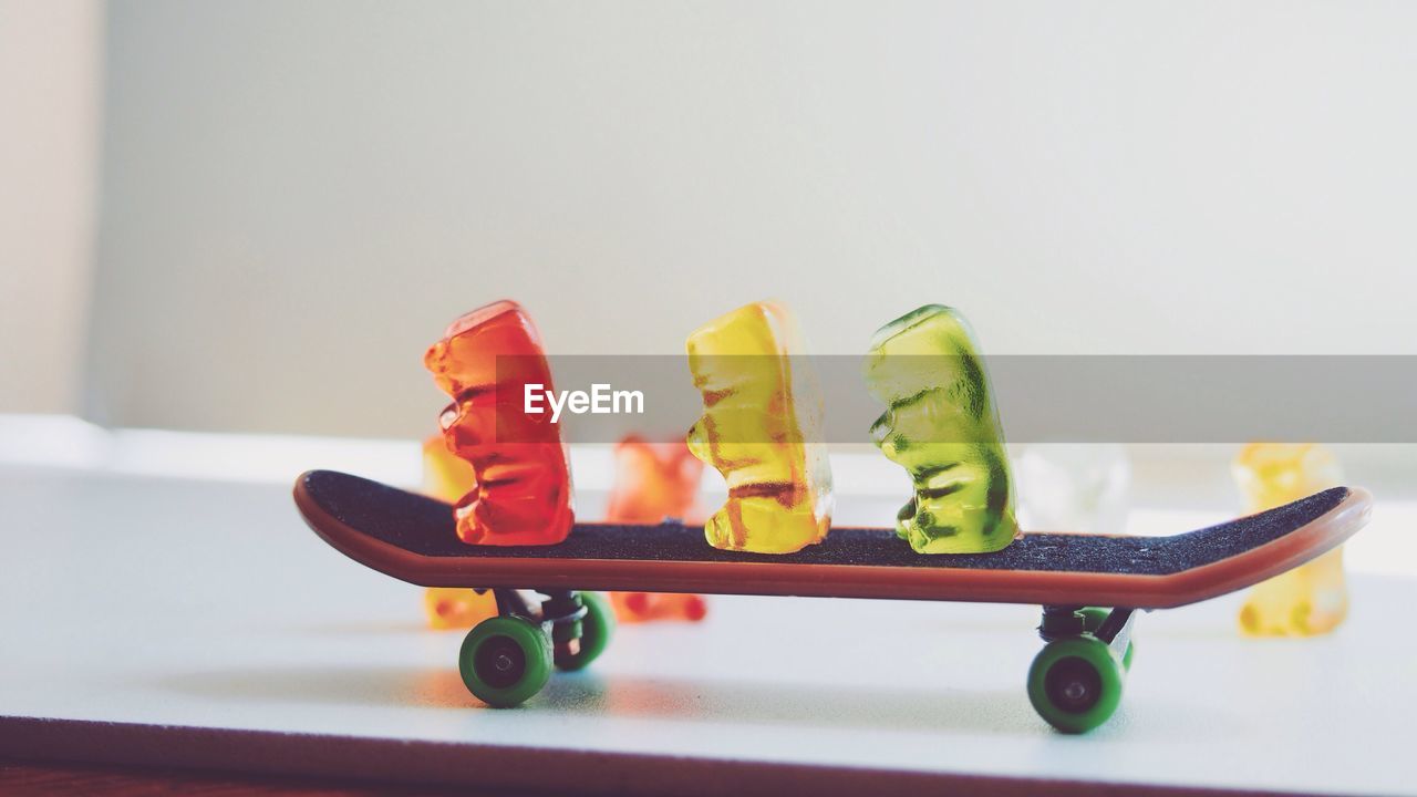 Close-up of colorful gummi bears on skateboard at table