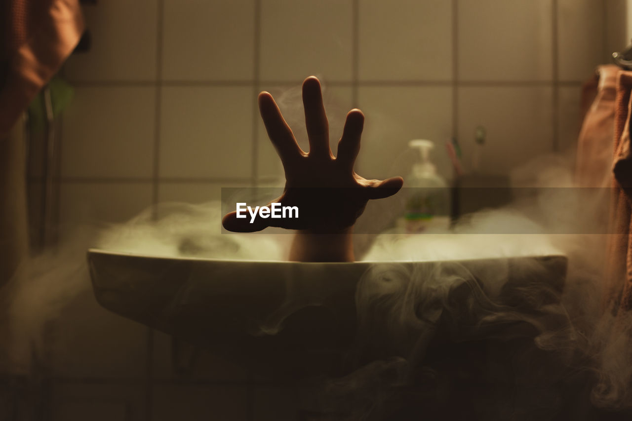 Cropped hand of person in bathroom sink