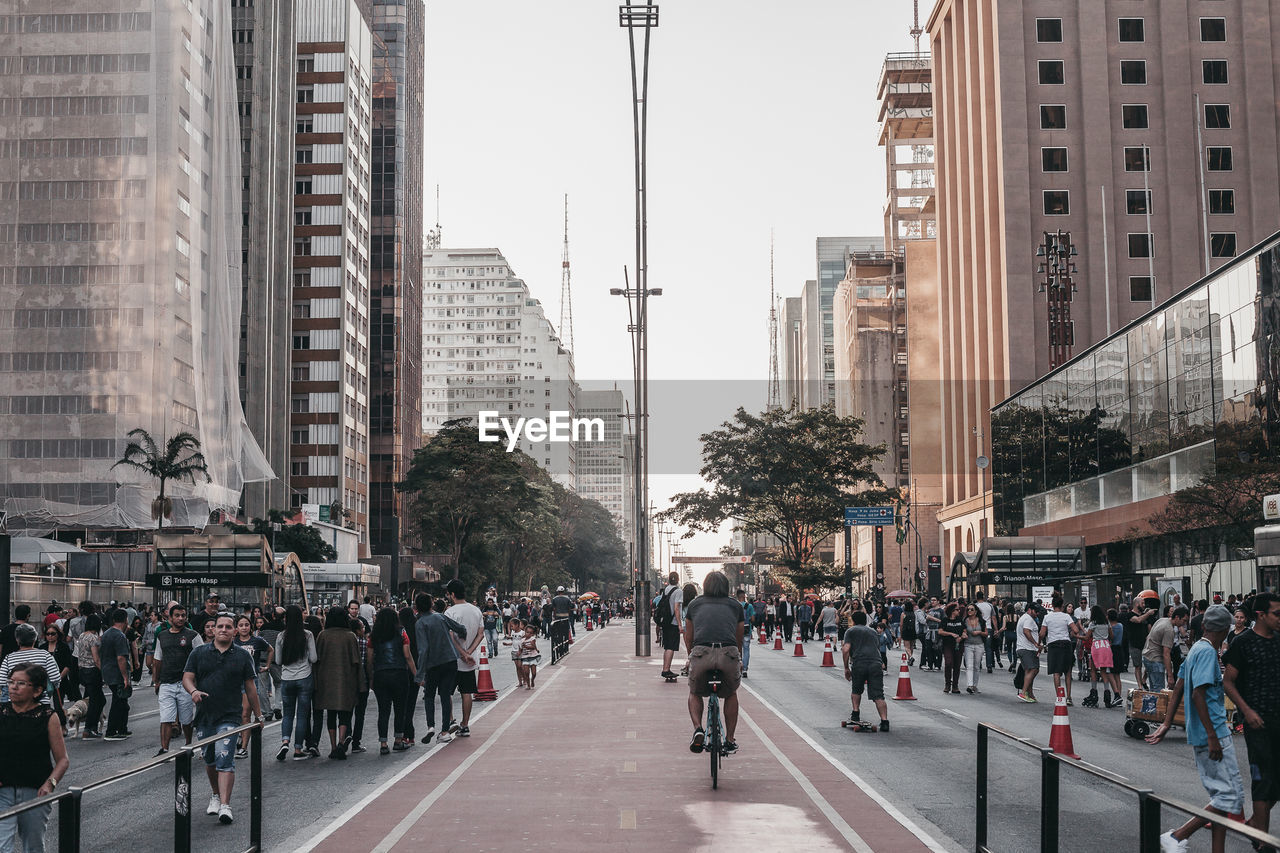 PEOPLE ON CITY STREET AMIDST BUILDINGS IN MODERN OFFICE