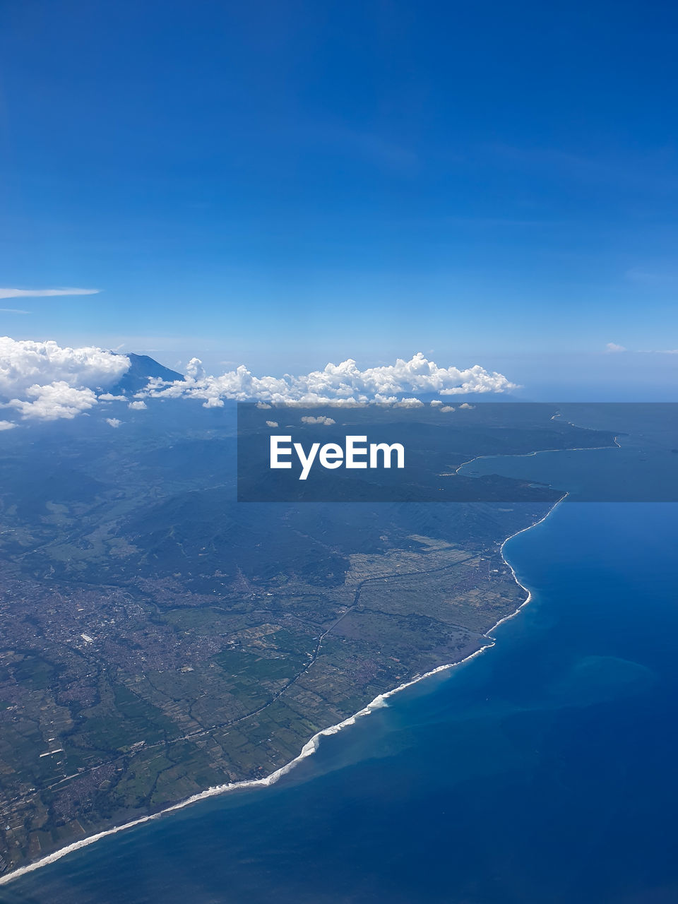 Aerial view of sea and mountains against blue sky