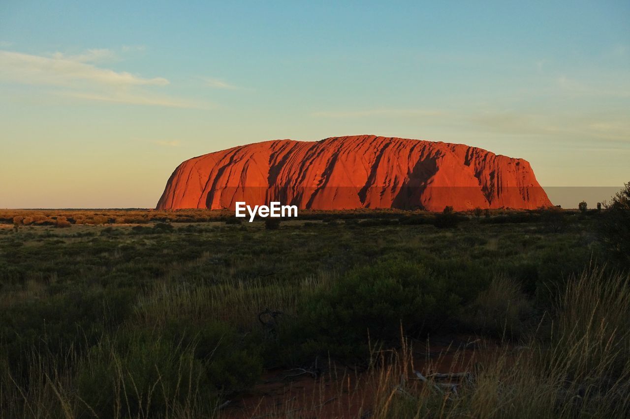 Rock formations on field against sky during sunset