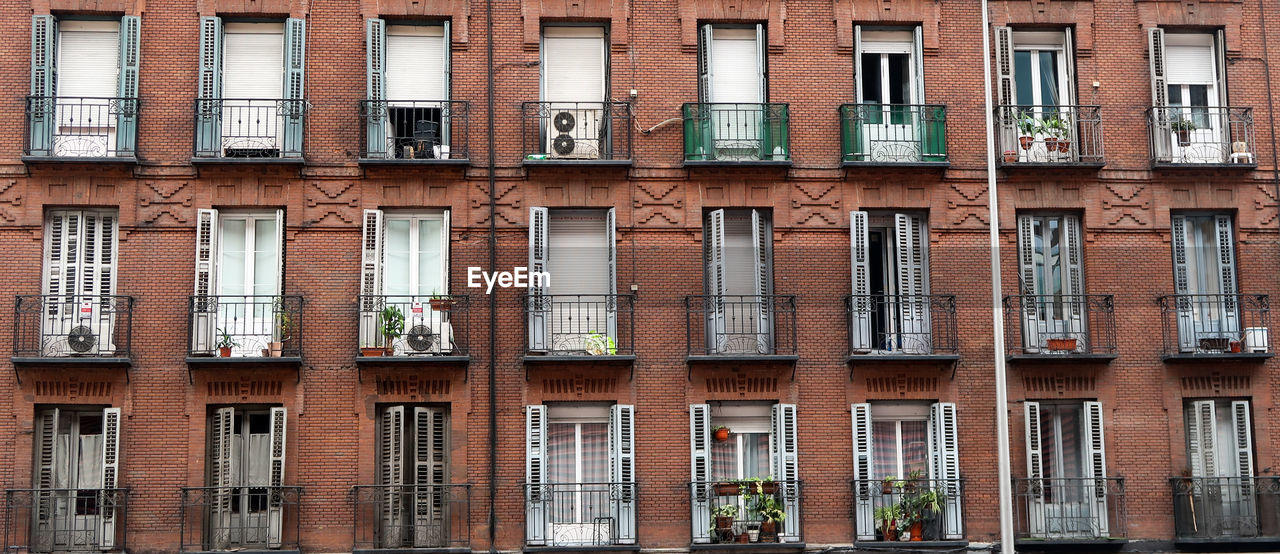 Red brick facade with wrought iron balconies in madrid, spain