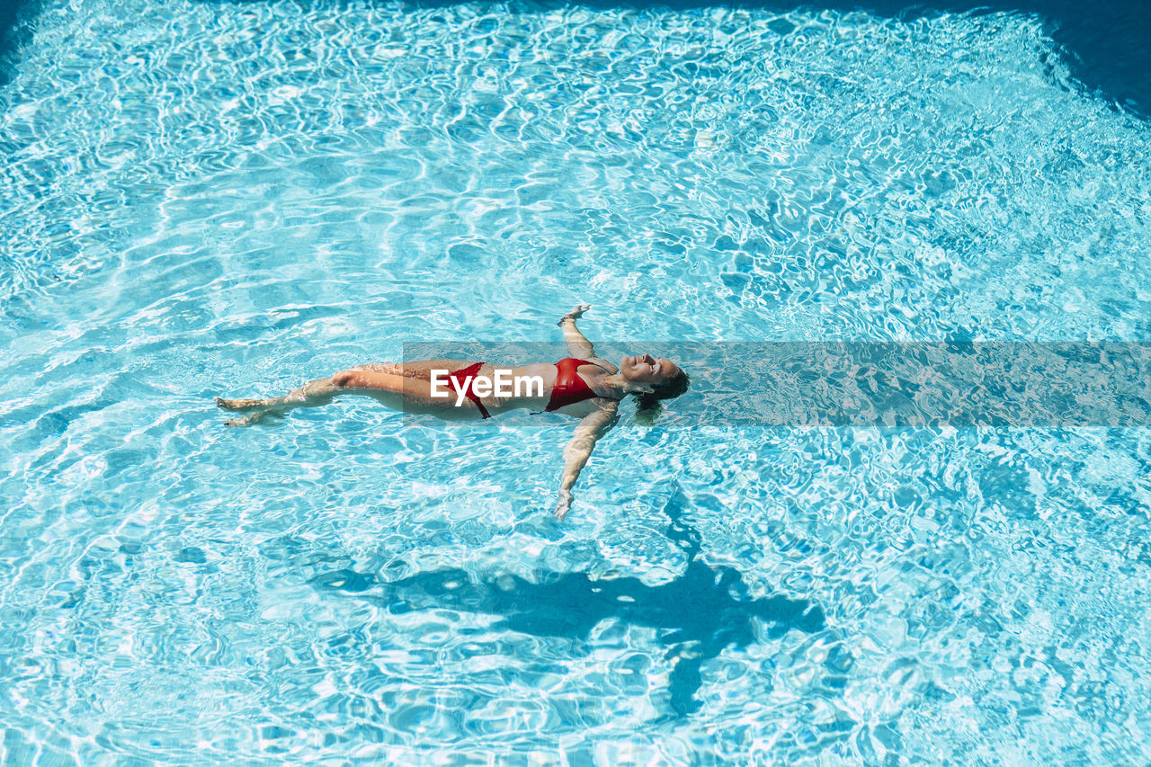 High angle view of woman floating in swimming pool