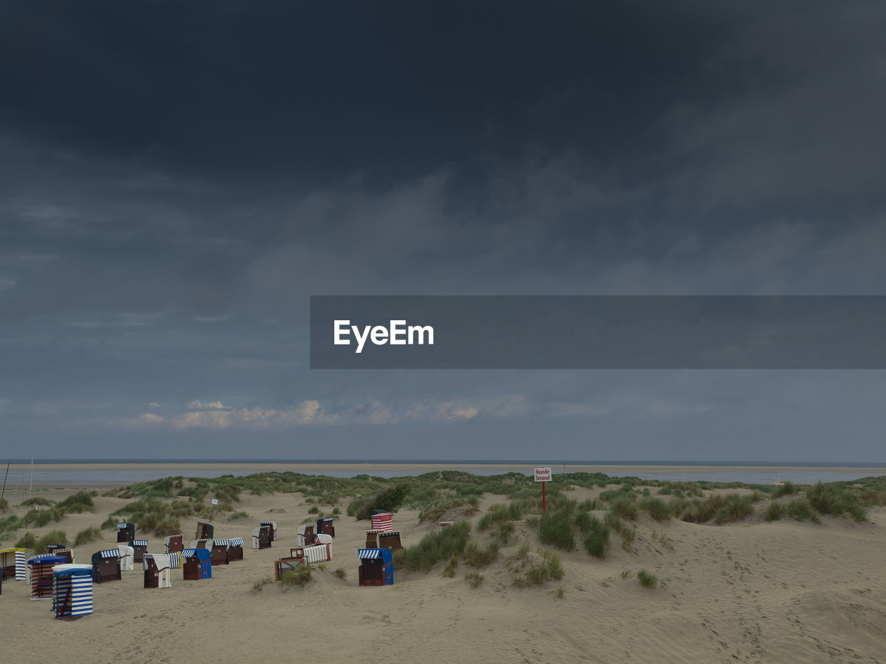 View of hooded chairs on beach against cloudy sky