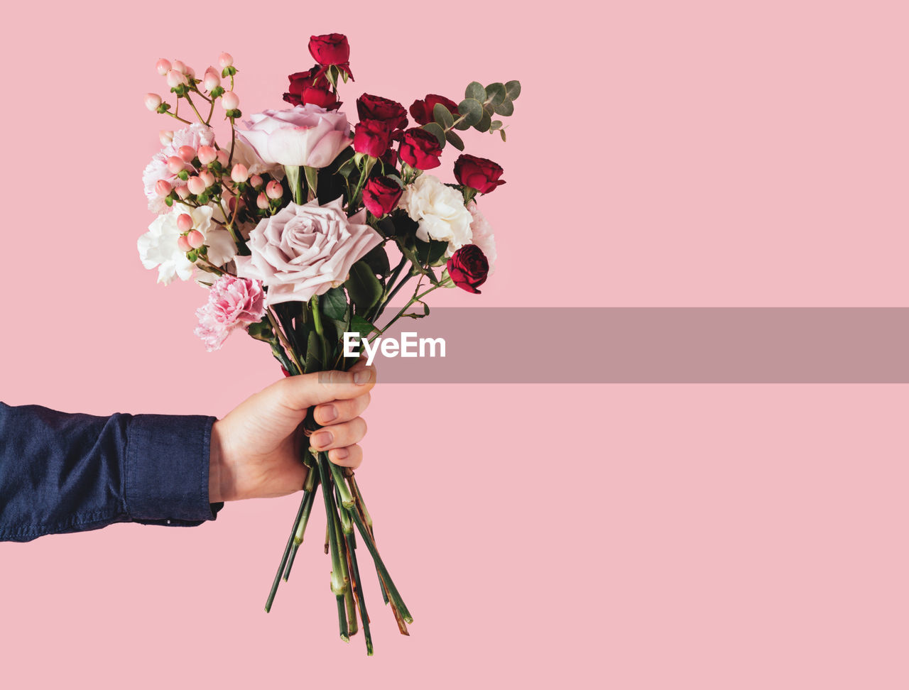 Male hand holding a beautiful bouquet on a pink background.birthday,mother's or valentine's day gift