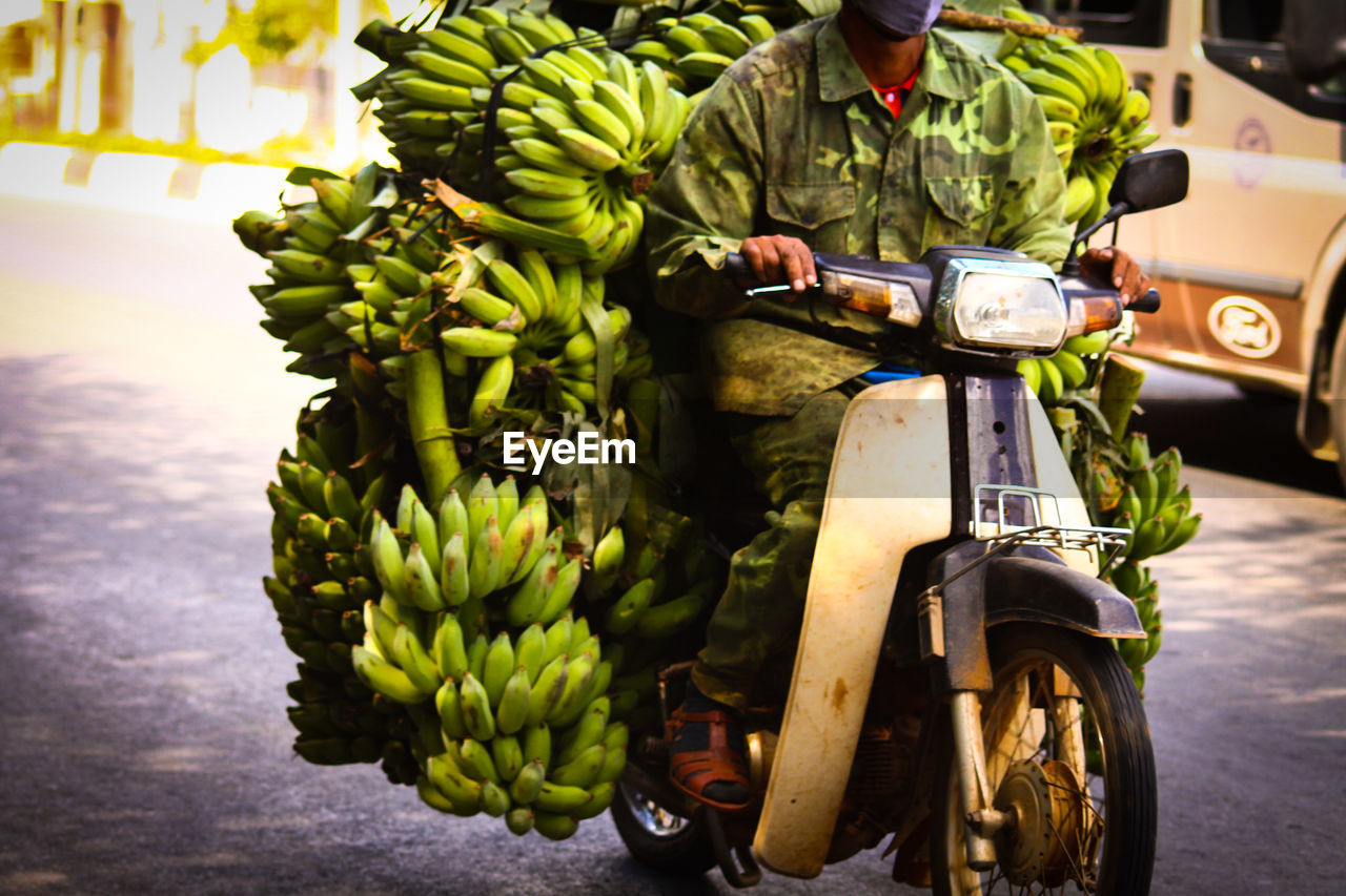 MIDSECTION OF MAN WITH FRUITS ON MOTORCYCLE