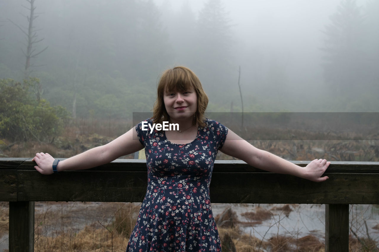 Woman standing by railing in forest