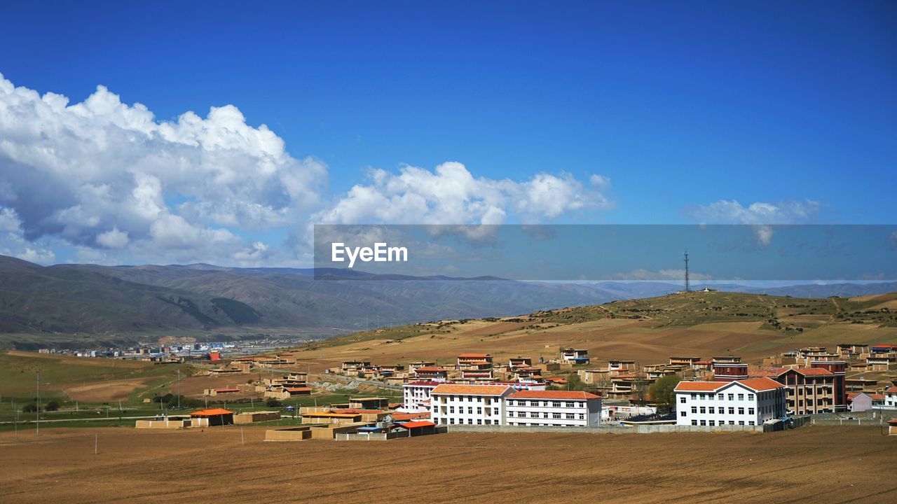 Houses on landscape against cloudy sky