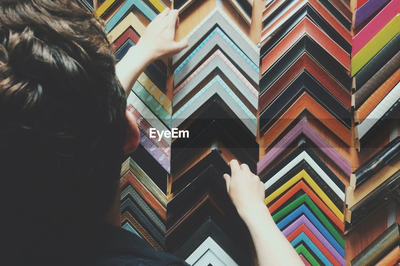 Rear view of man selecting picture frames in store