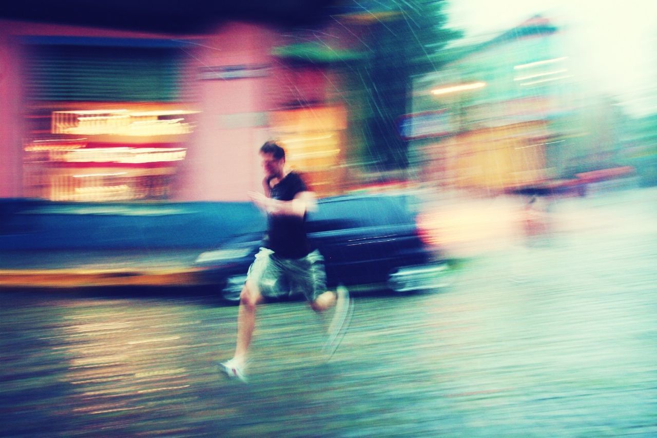 BLURRED MOTION OF WOMAN IN ILLUMINATED CITY AT NIGHT