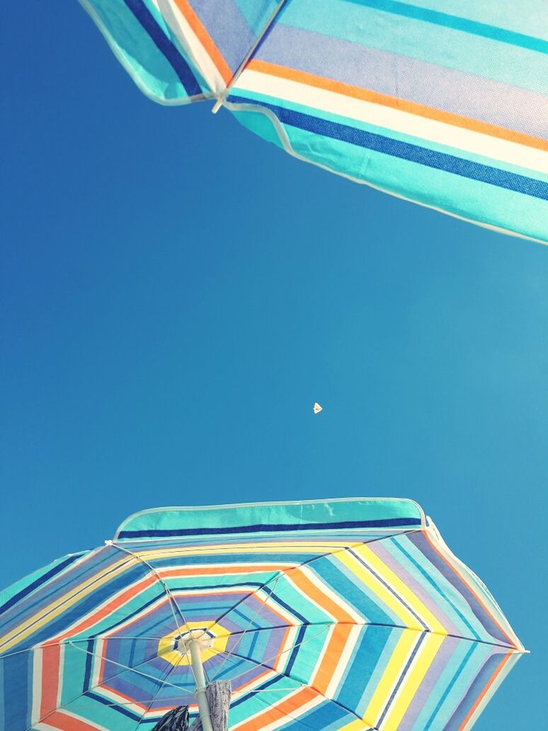 Colorful parasols against clear blue sky
