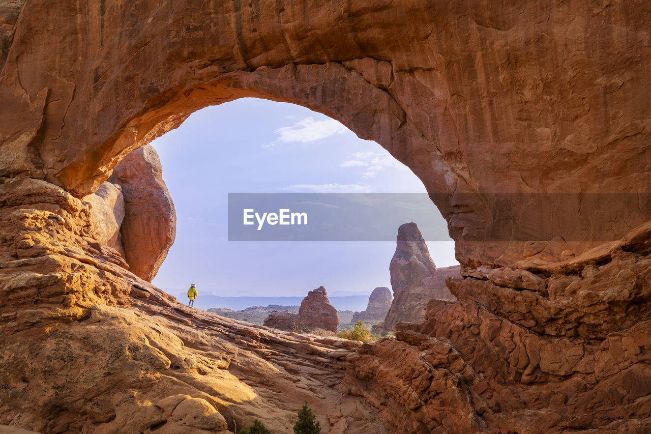 Female hiker framed in the north window against blue sky in arches