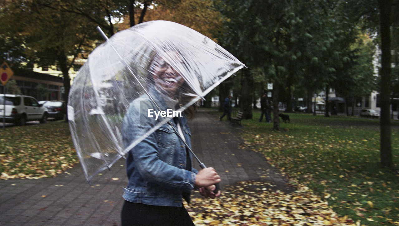 PORTRAIT OF WOMAN HOLDING UMBRELLA WHILE STANDING OUTDOORS