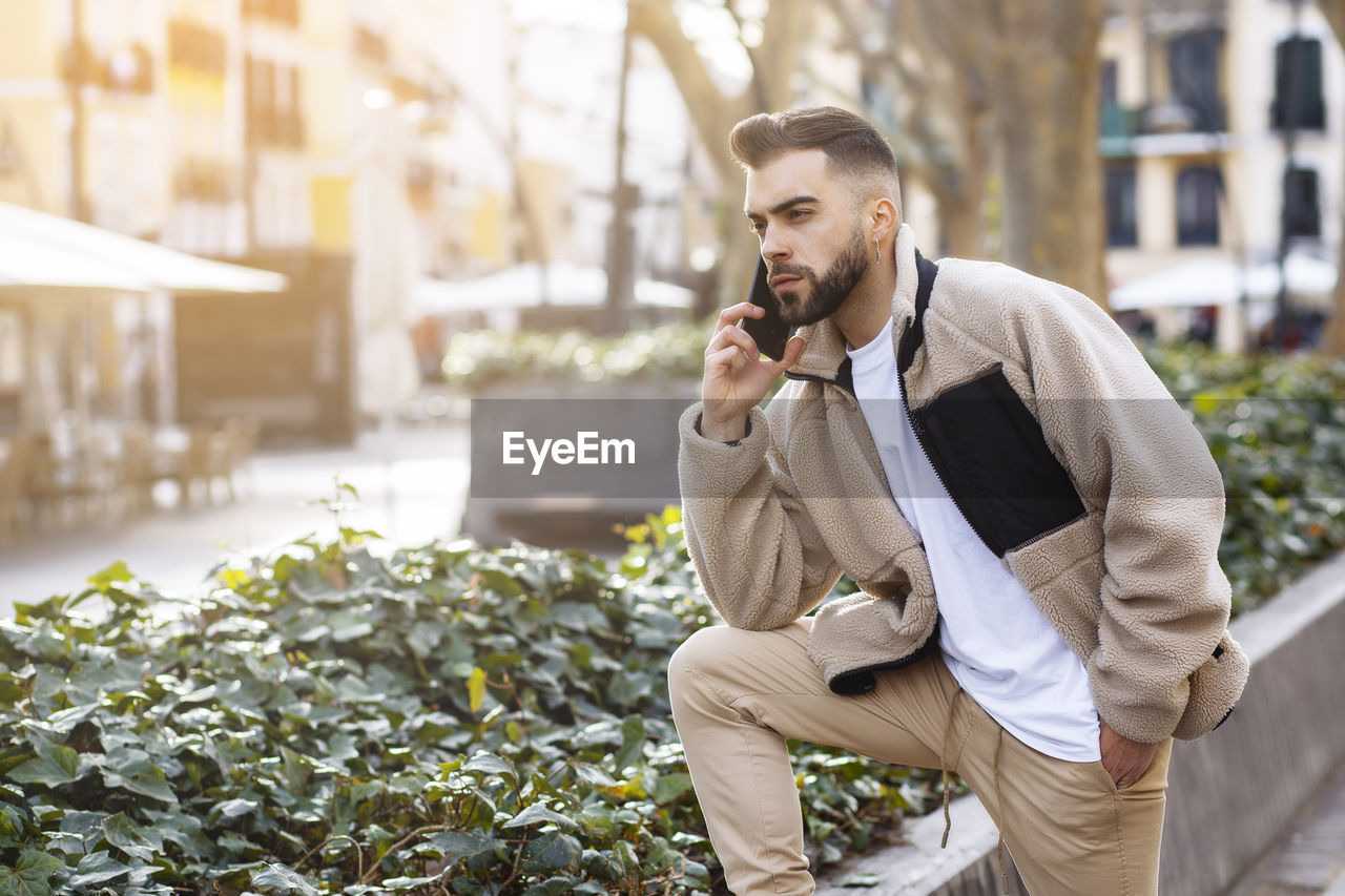 Portrait of a young man talking on the mobile phone while waiting person