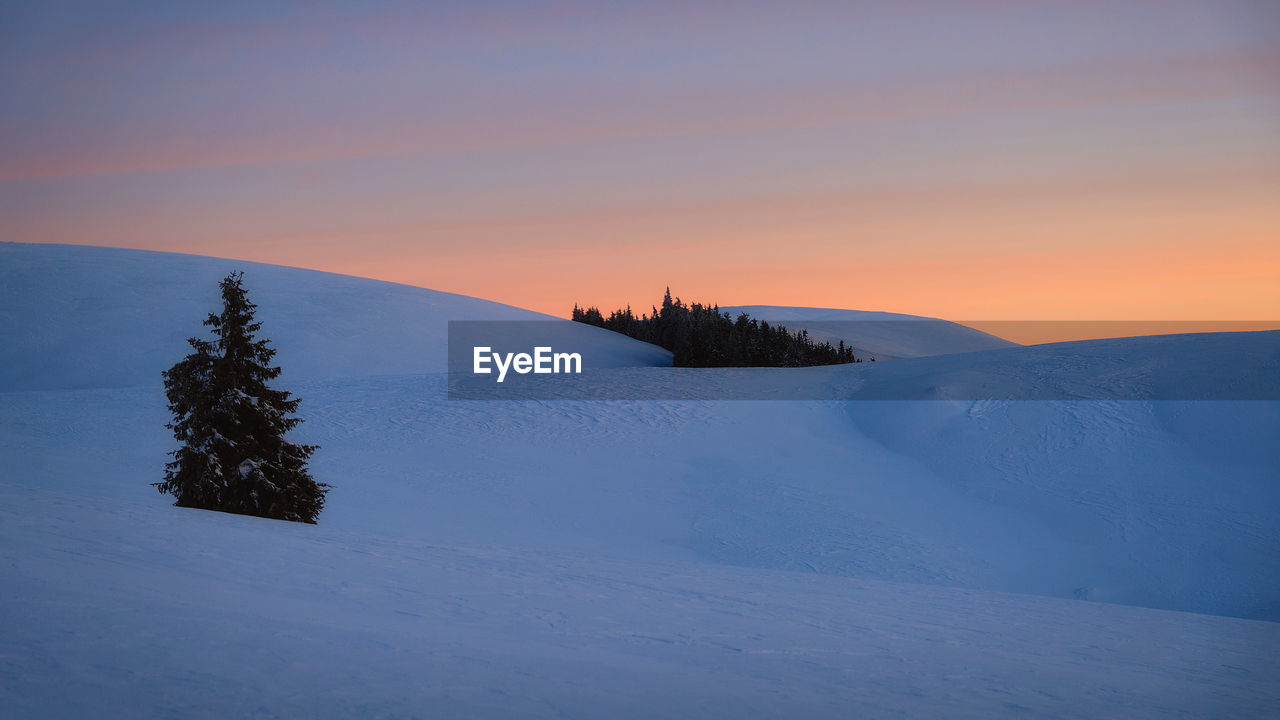 Scenic view of snow covered landscape against sky during sunset