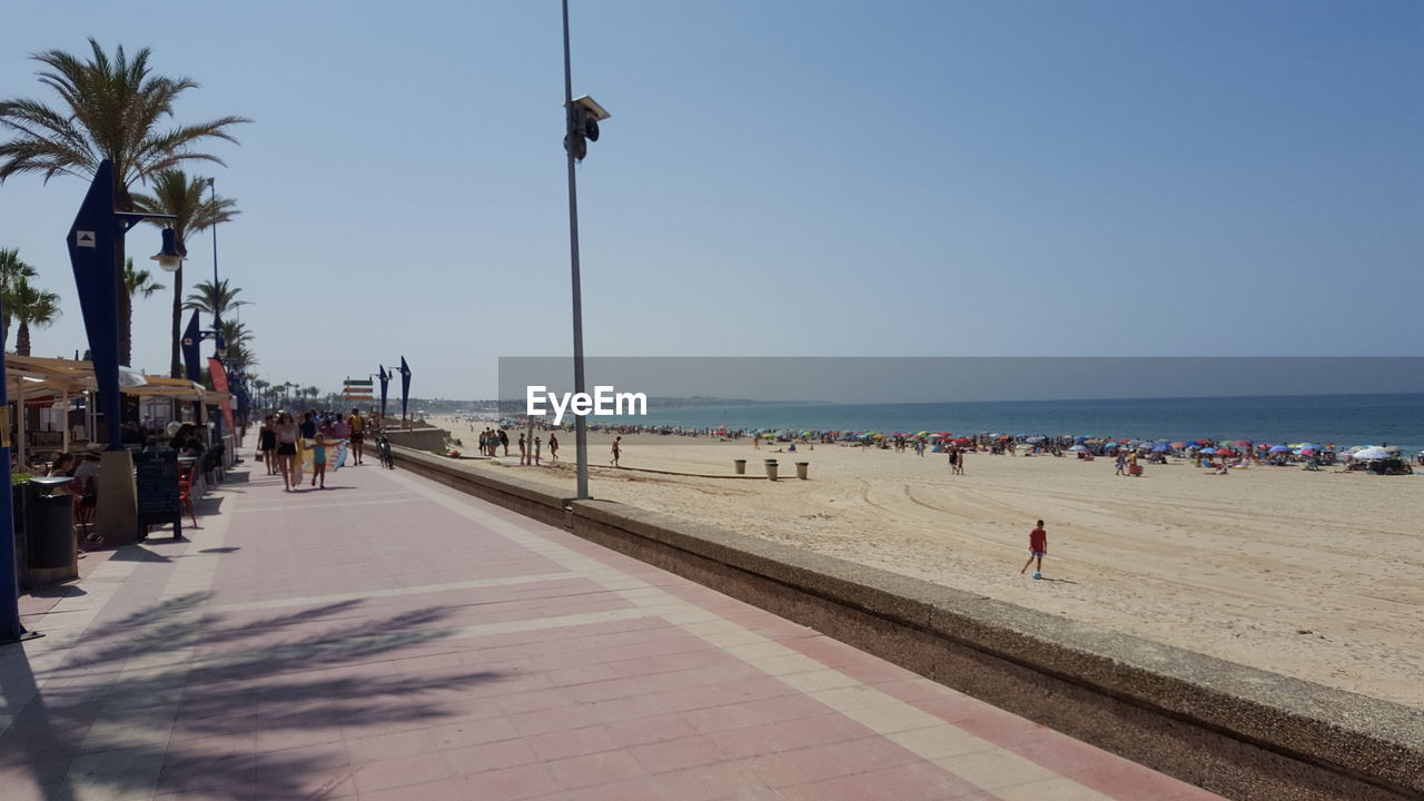 PEOPLE AT BEACH AGAINST CLEAR SKY